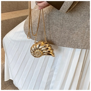 Detail of creative shell-shaped gold metal evening bag with glossy spiral texture and chain