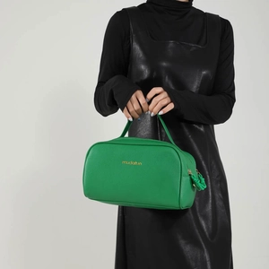 Vibrant green PU leather double zipper cosmetic bag held by a model with gold logo