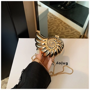 Detailed close-up of a gold nautilus-shaped clutch bag with luxury metallic spiral texture