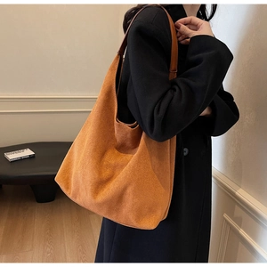 Close-up of caramel suede hobo bag with a brown leather strap in a minimalist setting