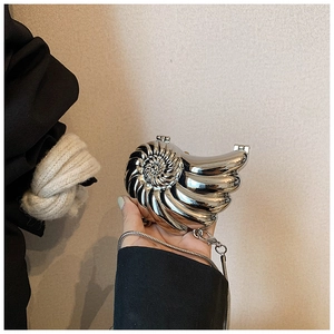 Detail of silver nautilus-shaped clutch bag with polished metallic finish and chain strap