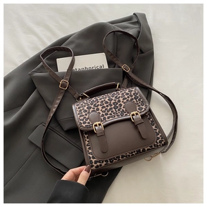 Detail shot of leopard print flap and gold-tone buckle on the brown leather backpack