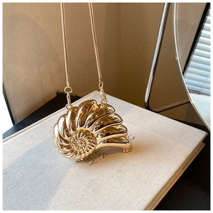 Close-up of golden shell-shaped evening bag with spiral texture and sleek snake chain