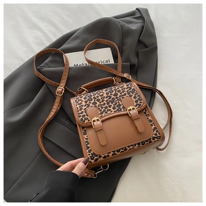 Detailed close-up of vintage leopard print backpack with brown leather patchwork and buckles