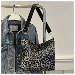 Detailed view of leopard print tote bag featuring black wide strap and gold metal buckles