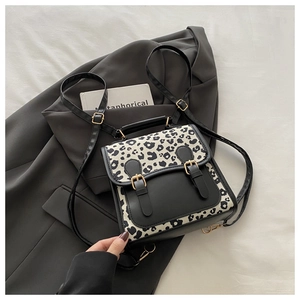 Detail of leopard print backpack with faux leather flap and decorative metal buckles
