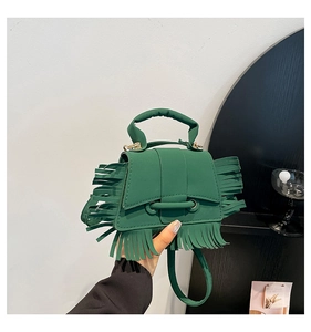 Détail d'un sac à main vert avec longues franges et fermeture à boucle annulaire chic