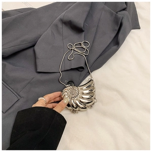 Detailed macro view of a mini silver nautilus shell bag with a thin metal snake chain strap