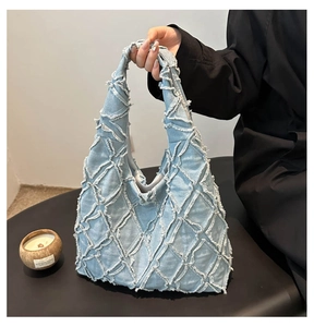 Détail du cabas en denim bleu clair avec bords effilochés matelassés et style vintage