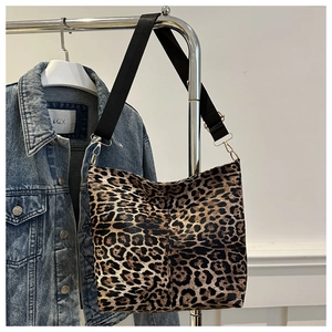 Detail of leopard print tote bag featuring black nylon strap and gold metal hardware