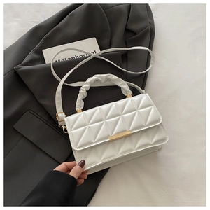 Detail of white quilted crossbody bag with golden clasp and textured handle