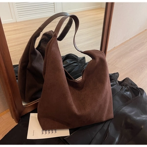 Detail of a large brown suede hobo tote bag with smooth leather shoulder strap
