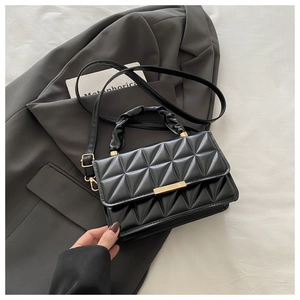 Close-up of quilted pattern on black faux leather crossbody bag with gold hardware