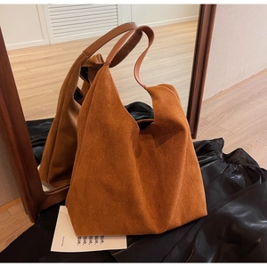 Detail view of large brown suede tote bag with leather strap and mirror reflection