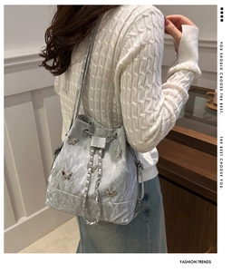 Détail du sac seau argenté à cordon avec papillons métalliques et bandoulière chaîne