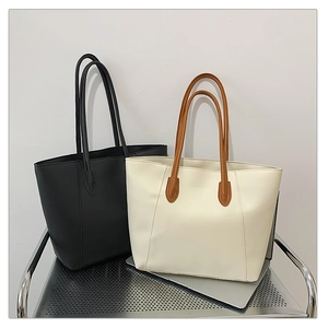 Detail view of large capacity tote bags in black and cream white with brown handles