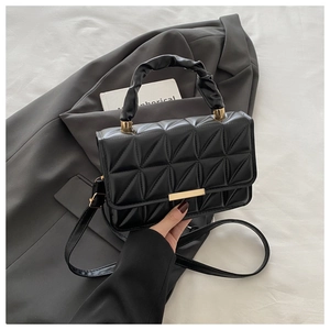 Detailed close-up of black quilted small square bag with elegant gold metal buckle hardware