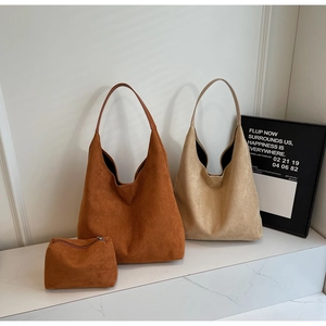 Detail of suede tote bag set with matching small zipper pouch on marble surface