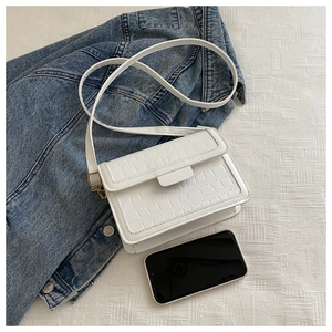 Close-up of white crocodile texture faux leather crossbody bag with gold hardware detail