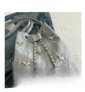 Détail du sac seau bleu clair avec papillons métalliques et texture plissée