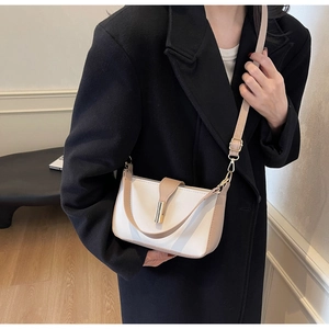 Detail of minimalist white and camel crossbody bag worn with a black winter coat