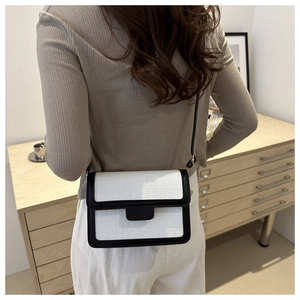 Detail of a color-block crossbody bag with crocodile texture worn over the shoulder