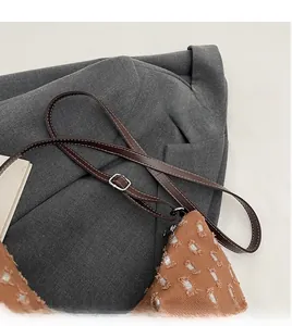Detail of dark brown adjustable strap and silver metal buckle on a sequined canvas tote