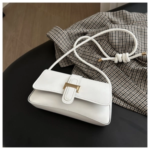 Detail of white baguette shoulder bag with gold metal buckle and knotted rope strap