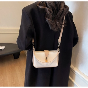 Detail view of the contrast color crossbody bag with gold buckle on a model shoulder