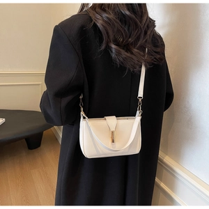 Detailed view of white minimalist crossbody bag with gold metallic lock on black coat