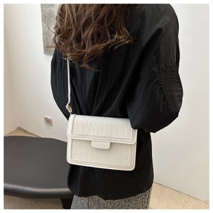 Detailed side view of a white crocodile pattern shoulder bag worn by a model