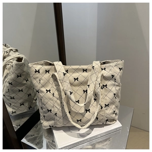 Detailaufnahme der cremefarbenen Cord-Tasche mit Rautenmuster und Schleifen-Deko