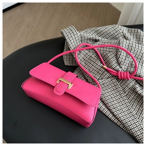 Detail of rose pink rectangular shoulder bag with golden metal clasp on black surface