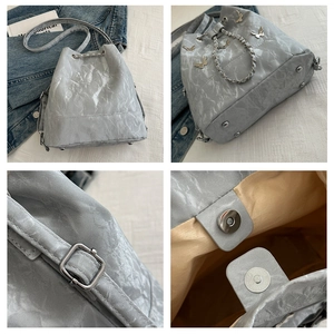 Détails du sac seau gris avec texture ondulée, papillon en métal et fermeture magnétique