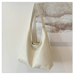 Detail view of large cream hobo tote bag with soft leather texture and wide shoulder strap