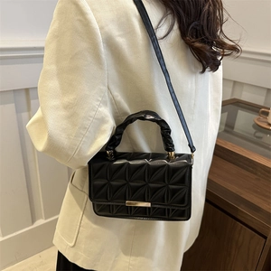 Quilted crossbody bag with ruched top handle and gold clasp on a beige background