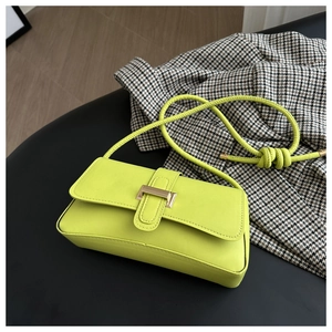 Detail of neon green leather shoulder bag with gold clasp and knotted strap detail