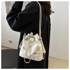 Détail du sac seau blanc à cordon avec breloques papillons argentées et chaîne