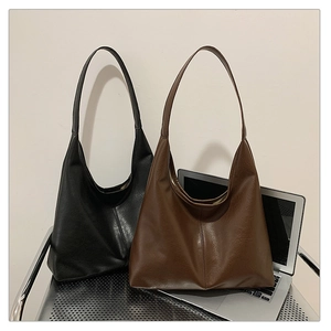 Detail showing two vintage faux leather tote bags in black and brown colors stacked on desk
