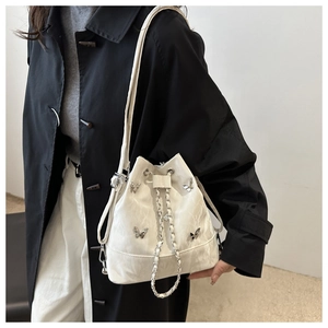 Détail du sac seau blanc à texture marbre avec breloques papillon porté par le mannequin