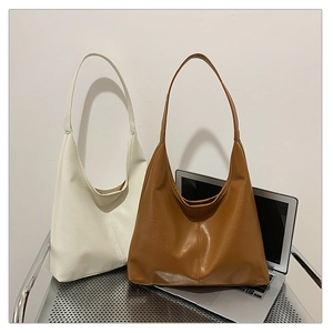 Minimalist faux leather tote bags in cream and caramel brown shown on a metal cart