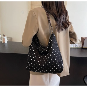 Close-up of black polka dot hobo bag with white tufted dots and brown leather strap