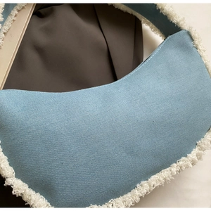 Détail du sac en toile bleu clair avec bordure en polaire blanche et texture en sergé