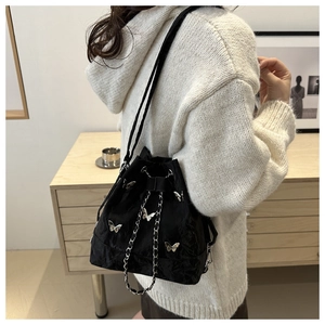 Détail du sac seau noir plissé avec breloques papillon argentées et chaîne d'épaule