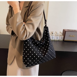 Detailed texture of black and white polka dot tote bag with brown leather strap