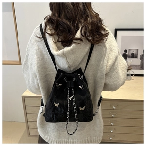 Détail de la boucle papillon argentée sur sac à cordon plissé noir avec chaîne