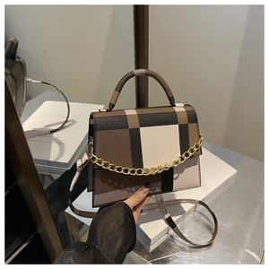 Detail of checkered shoulder bag with golden chain and sleek leather handle design