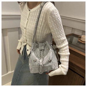 Gros plan d'un sac seau argenté avec papillons 3D et une bandoulière en chaîne métal
