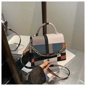 Detail of color-block geometric small square bag with gold chain and adjustable strap