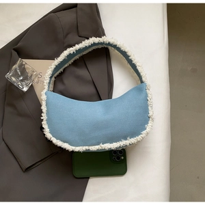 Détail du sac hobo en denim bleu clair avec bordure en fausse fourrure blanche